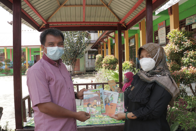 Komite sekolah SDN 003/V Kuala Tungkal memberikan bantuan buku kepada kepala SDN 003 Kuala Tungkal.