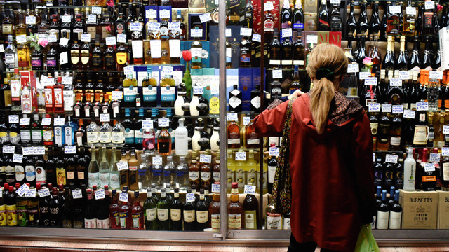 Seorang wanita melihat botol minuman alkohol. Foto: Mariana Nedelcu/Reuters