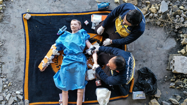 Anggota pertahanan sipil Suriah, White Helmets, menggunakan boneka untuk menunjukkan keterampilan penyelamatan mereka selama syuting video untuk film instruktif yang ditujukan untuk penyelamat Ukraina, di kota Ariha Suriah, Suriah. Foto: Omar HAJ KADOUR/AFP