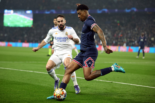 Pemain Real Madrd Dani Carvajal berebut bola dengan pemain Paris Saint-Germain (PSG) Presnel Kimpembe pada pertandingan 16 besar Liga Champions di Parc des Princes, Paris, Prancis, Rabu (16/2/2022).  Foto: Sarah Meyssonnier/REUTERS