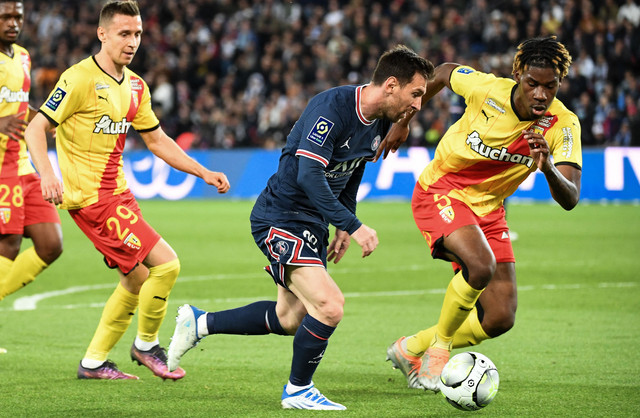 Penyerang Paris Saint-Germain Lionel Messi (tengah) berebut bola dengan bek Lens asal Prancis Christopher Wooh (kanan) pada pertandingan sepak bola L1 Prancis antara Paris-Saint Germain (PSG) dan RC Lens di Stadion The Parc des Princes (23/4/2022). Foto: BERTRAND GUAY / AFP