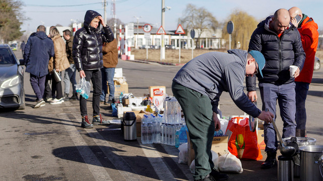 Orang Rumania menyajikan teh, air, dan makanan kepada orang-orang yang melintasi perbatasan dari Ukraina ke Rumania di Siret Customs, di Suceava, Rumania, Jumat (25/2/2022).
 Foto: Casian Mitu 