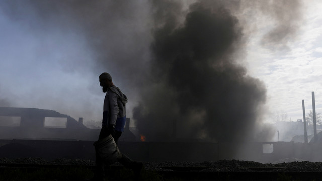 Seseorang membawa ember saat dia bekerja untuk memadamkan api di pabrik yang terbakar akibat serangan Rusia, di Kharkiv, Ukraina, Sabtu (30/4/2022). Foto: Ricardo Moraes/REUTERS