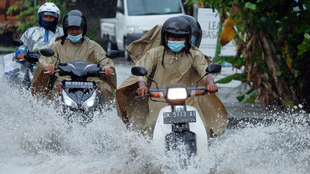 Sejumlah pengendara sepeda motor menerobos banjir yang menggenangi kawasan Jalan Gunung Salak, Denpasar, Bali, Senin (21/2/2022). Foto: Nyoman Hendra Wibowo/ANTARA FOTO