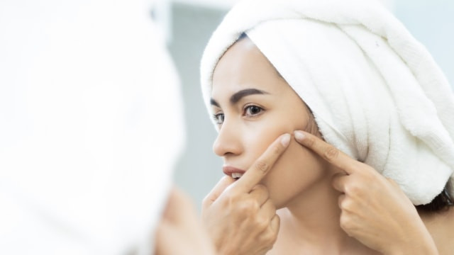 Ilustrasi perempuan sedang memperhatikan jerawat. Foto: Shutterstock