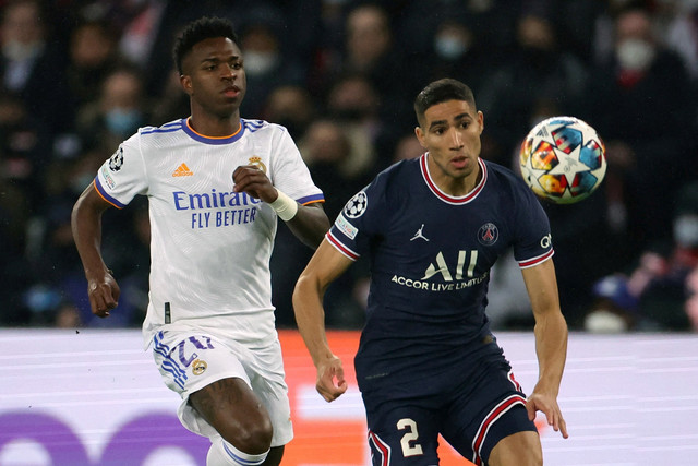 Pemain Real Madrd Vinicius Junior berebut bola dengan pemain Paris Saint-Germain (PSG) Achraf Hakimi pada pertandingan 16 besar Liga Champions di Parc des Princes, Paris, Prancis, Rabu (16/2/2022).  Foto: Sarah Meyssonnier/REUTERS