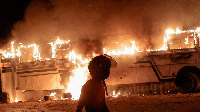 Seorang demonstran berjalan di dekat sebuah bus yang dibakar dekat kediaman Presiden Sri Lanka Gotabaya Rajapaksa selama protes krisis ekonomi di Kolombo, Sri Lanka pada Kamis (31/3/2022). Foto: Dinuka Liyanawatte/REUTERS