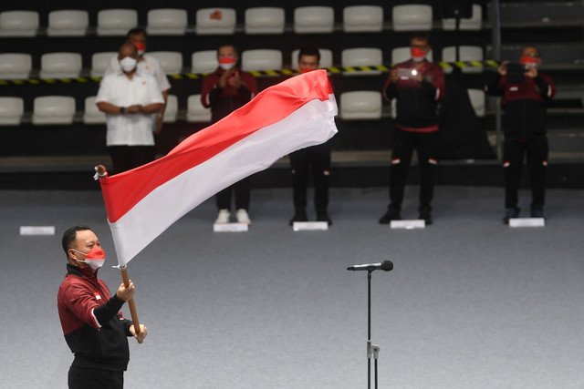 Chef de Mission (CdM) Kontingen Indonesia Ferry J Kono mengibarkan bendera merah putih saat upacara pengukuhan kontingen tim Indonesia untuk Sea Games Vietnam di Jakarta, Minggu (8/5/2022). Foto: Akbar Nugroho Gumay/ANTARA FOTO
