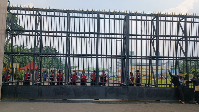 Beberapa polisi mulai bersiaga di balik gerbang gedung DPR RI pada Senin (11/4). Foto: Farusma Okta Verdian/kumparan