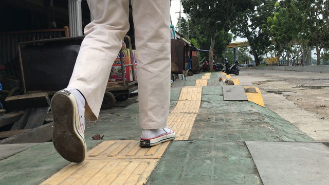 SEORANG pejalan kaki melintas di atas trotoar yang dibangun di Jalan Meranti, Senapelan, Pekanbaru. (FOTO: SELASAR RIAU/RAMADHI DWI PUTRA)