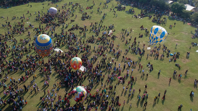Foto udara sejumlah warga menerbangkan balon udara yang ditambatkan di tanah saat "Balloon Attraction Pekalongan 2022" di Lapangan Mataram, Kota Pekalongan, Jawa Tengah, Minggu (8/5/2022). Foto: Harviyan Perdana Putra/Antara Foto