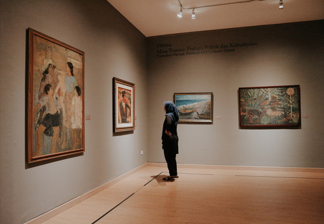 cara beli tiket museum macan. sumber foto : unsplash/perempuan berdiri di depan lukisan