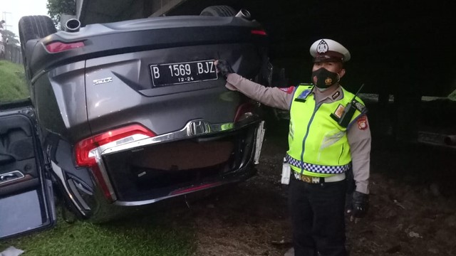 Polisi di lokasi kecelakaan mobil B 1569 BJZ yang lepas kendali hingga terbalik di Jl. Ring Road Puri Kembangan samping tol Jakarta-Tangerang arah Cengkareng. Foto: Twitter/@TMCPoldaMetro