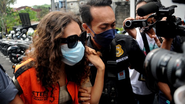 Warga negara Amerika Serikat, Heather Mack, digiring petugas imigrasi setelah memperoleh status bebas murni di Lapas Kerobokan, Badung, Bali, Jumat (29/10/2021). Foto: Sonny Tumbelaka/AFP