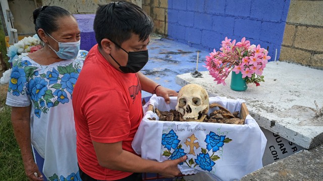Warga di Pomuch membersihkan tengkorak seorang kerabat selama ritual dalam perayaan Hari Orang Mati, di Negara Bagian Campeche, Meksiko. Foto: Luis Perez / AFP