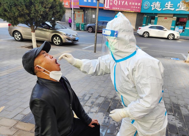 Pekerja medis mengambil sampel swab dari warga untuk diuji virus corona di China. Foto: STR / AFP
