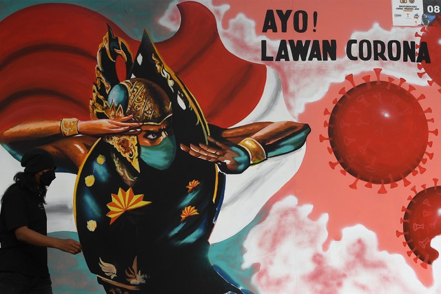 Warga melintas di depan tentang mural COVID-19 di Jakarta, Selasa (2/11/2021). Foto: Sigid Kurniawan/Antara Foto