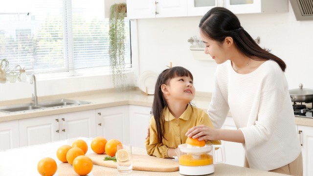 Anak makan atau minum jeruk peras dengan kandungan vitamin C. Foto: Shutter Stock