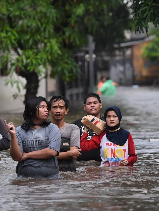 Warga melintasi banjir di Pela Mampang, Jakarta, Minggu (7/11/2021). Foto: Akbar Nugroho Gumay/Antara Foto