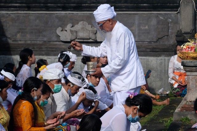 Pemuka Agama Hindu memercikkan air suci saat persembahyangan Hari Raya Galungan di Pura Puseh Desa Adat Kedisan, Jembrana, Bali, Rabu (10/11/2021). Foto: Nyoman Hendra Wibowo/Antara Foto