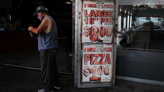 Seorang pria makan pizza seharga $1 di wilayah Brooklyn, New York City, AS. Foto: Spencer Platt/Getty Images