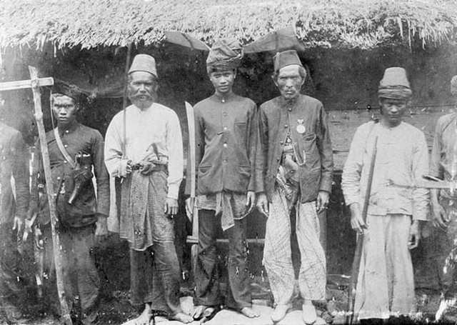 Seorang pejuang Aceh (tengah) dengan kelewang. Dok. KITLV  