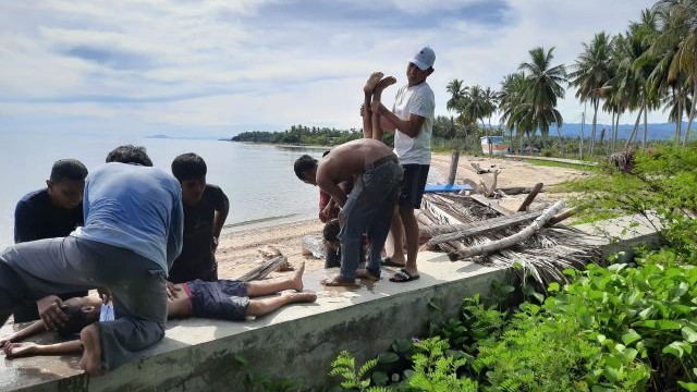 Sejumlah warga berupaya melakukan pertolongan pertama kepada kedua anak kakak beradik yang tenggelam di Pantai Tomini, Desa Pelawa Baru, Kecamatan Parigi Tengah, Kabupaten Parigi Moutong, Minggu (14/11). Foto: Istimewa
