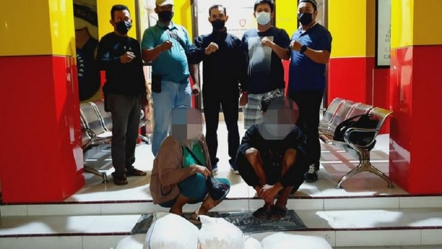 Dua pelaku penyelundupan miras jenis cap tikus saat diamankan di Mapolsek Palu Barat, Senin (15/11). Foto: Istimewa