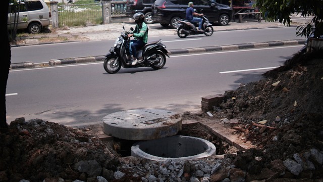 Pengendara motor melintasi proyek galian sumur resapan di kawasan Duren Sawit, Jakarta Timur, Selasa (18/11/2021). Foto: Jamal Ramadhan/kumparan