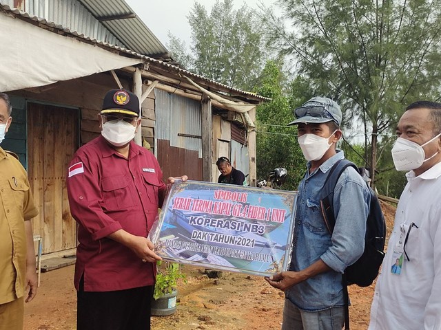 Bupati Karimun, Aunur Rafiq (kiri) menyerahkan bantuan kapal kepada kelompok nelayan secara simbolis. Foto: Istimewa