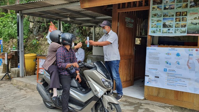 Seorang wisatawan sedang melakukan scan QR Code lewat aplikasi PeduliLindungi di TPR Pantai Gunungkidul. Foto: Sandra/Tugu Jogja