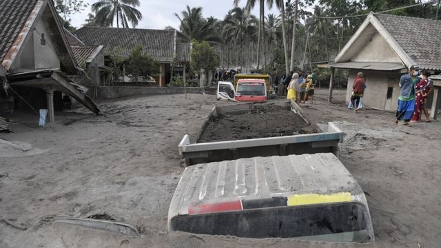 Warga mengamati truk pengangkut pasir yang tertimbun abu Gunung Semeru di Desa Sumberwuluh, Kabupaten Lumajang, Provinsi Jawa Timur, Minggu (5/12/2021). Foto: Zabur Karuru/Antara Foto