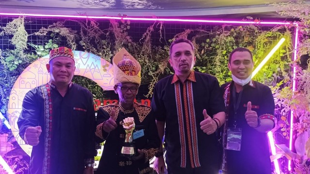 Keuchik (kepala desa) Gampong Nusa, M Yasin (kedua kiri) dengan piala ADWI 2021. Dok. Disbudpar Aceh