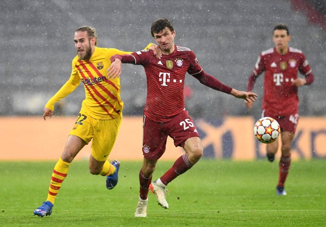 Pemain Bayern Muenchen Thomas Mueller duel dengan Oscar Mingueza dari FC Barcelona saat pertandingan di Allianz Arena, Munich, Jerman. Foto: Andreas Gebert/Reuters