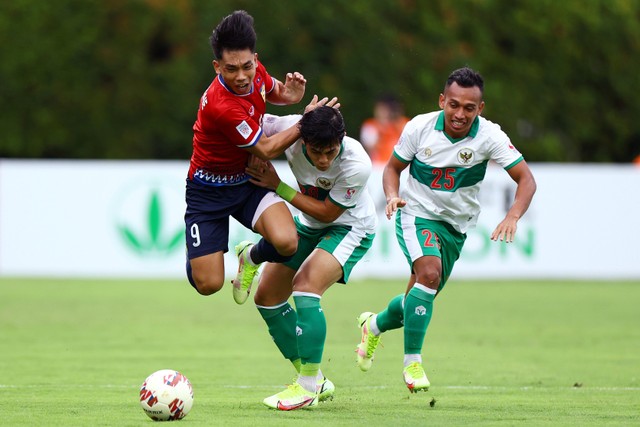 Pemain Laos Kydavone Souvanny duel dengan pemain Indonesia Alfeandra Dewangga Santosa dan Irfan Samaling Kumi pada pertandingan Grup B AFF Suzuki Cup di Stadion Bishan, Singapura. Foto: Yong Teck Lim/Getty Images