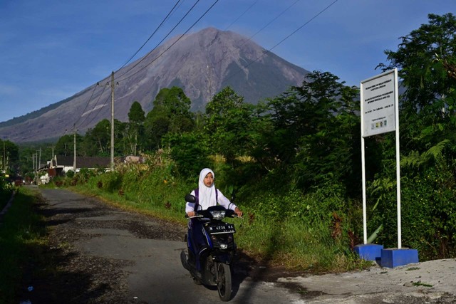 Seorang anak berangkat sekolah dengan latar belakang Gunung Semeru di Sumbermujur, Candipuro, Lumajang, Jawa Timur, Selasa (14/12/2021). Foto: Budi Candra Setya/Antara Foto