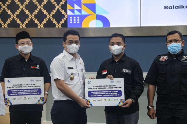 Wakil Gubernur Provinsi DKI Jakarta, Ahmad Riza Patria bersama Direktur Utama PAM Jaya, Priyatni Bambang Hernowo secara simbolis menyerahkan bantuan berupa 4.718 paket sembako yang dilakukan di Ruang Pola, Balaikota DKI Jakarta, Jakarta Pusat, pada Rabu (15/12/2021). Dok. Dompet Dhuafa