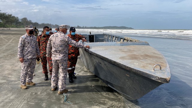 Petugas memeriksa kapal yang terbalik dan menewaskan beberapa orang di dalamnya, Johor, Malaysia. Foto: Reuters