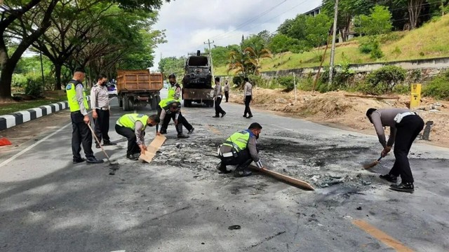Sejumlah anggota kepolisian sedang membersihkan ruas jalan akibat bentrokan yang terjadi pada Kamis (16/12). Foto: Istimewa.