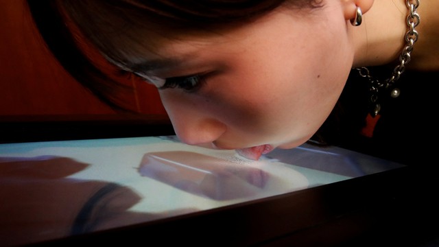 Mahasiswa Universitas Meiji, Yuki Hou, menjilat layar Taste the TV (TTTV), saat demonstrasi Taste the TV (TTTV), di universitas di Tokyo, Jepang, Rabu (22/12). Foto: Kim Kyung-Hoon/REUTERS