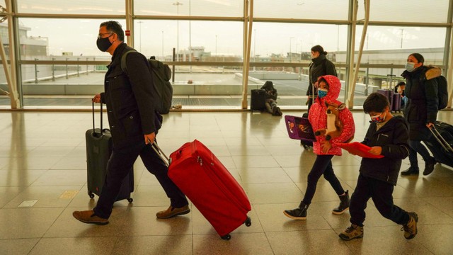 Penumpang berjalan di Bandara Internasional John F. Kennedy setelah maskapai mengumumkan banyak penerbangan yang dibatalkan selama penyebaran varian virus corona Omicron. Foto: DIEU-NALIO CHERY/REUTERS