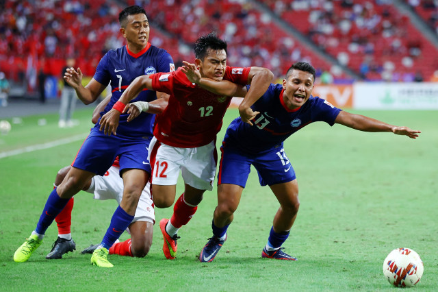 Pemain Timnas Indonesia Pratama Arhan Alif Rifai beraksi dengan Pemain Singapura Amy Recha dan Zulqarnaen Suzliman pada semifinal AFF Suzuki Cup di National Stadium Singapura, Sabtu (25/12). Foto: Yong Teck Lim/Getty Images