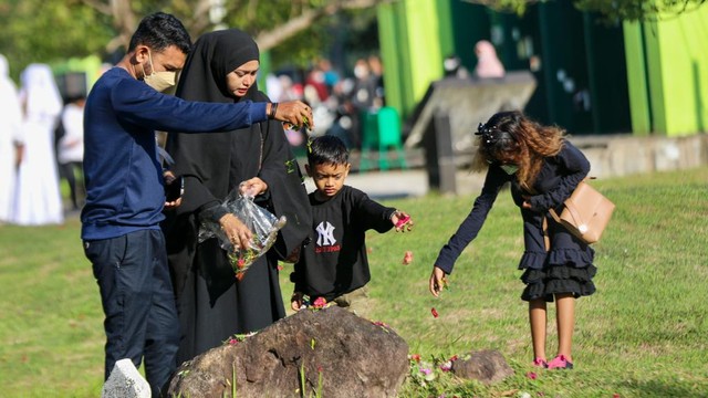 Warga menabur bunga di sebuah batu di kompleks kuburan massal tsunami Aceh. Foto: Suparta/acehkini