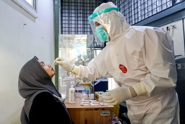 Petugas kesehatan melakukan tes swab kepada warga di pos screening Puskesmas Kecamatan Mampang Prapatan, Jakarta Selatan, Selasa (28/12/2021). Foto: Iqbal Firdaus/kumparan