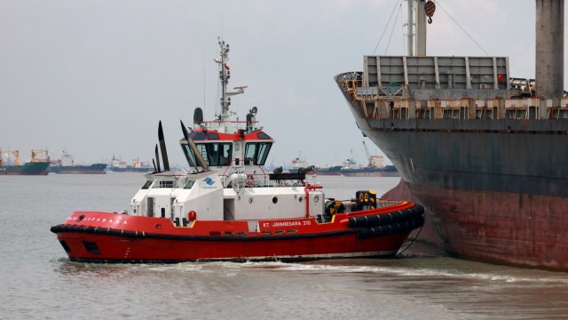Kapal tunda (tug boat) mendorong kapal kargo yang akan berlayar di Pelabuhan Tanjung Perak, Surabaya, Jawa Timur, Senin (3/12/2018). Foto: Antara/Didik Suhartono