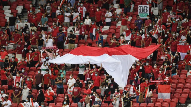 Suporter Indonesia menyemangati tim mereka sebelum pertandingan leg pertama final sepak bola AFF Suzuki Cup 2020 melawan Thailand di National Stadium, Singapura, 29 Desember 2021. Foto: Roslan RAHMAN / AFP