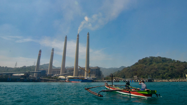 Nelayan melintasi di PLTU Suralaya di Cilegon. Foto: RONALD SIAGIAN / AFP
