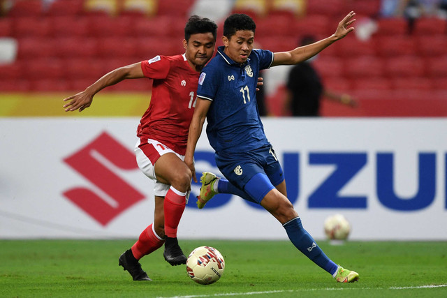 Asnawi Mangkualam Bahar (kiri) dari Indonesia berebut bola dengan Bordin Phala dari Thailand pada pertandingan leg kedua final sepak bola AFF Suzuki Cup 2020 Foto: Roslan RAHMAN / AFP