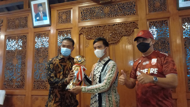 Pelatih kepala Persis Solo, Eko Purdjianto, menyerahkan Piala Liga 2 kepada Wali Kota Solo, Gibran Rakabuming Raka, di Loji Gandrung, Sabtu (01/01/2022). FOTO: Agung Santoso