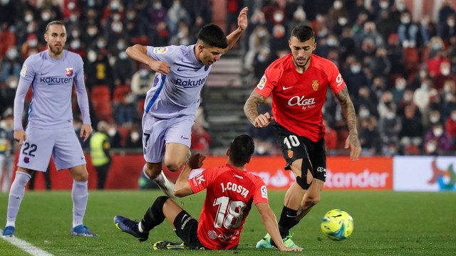 Pemain FC Barcelona Ilias Akhomach beraksi dengan pemain RCD Mallorca Jaume Costa dan Antonio Sanchez di Mallorca Stadium, Palma, Mallorca, Spanyol, Minggu (2/1/2022). Foto: Nacho Doce/REUTERS
